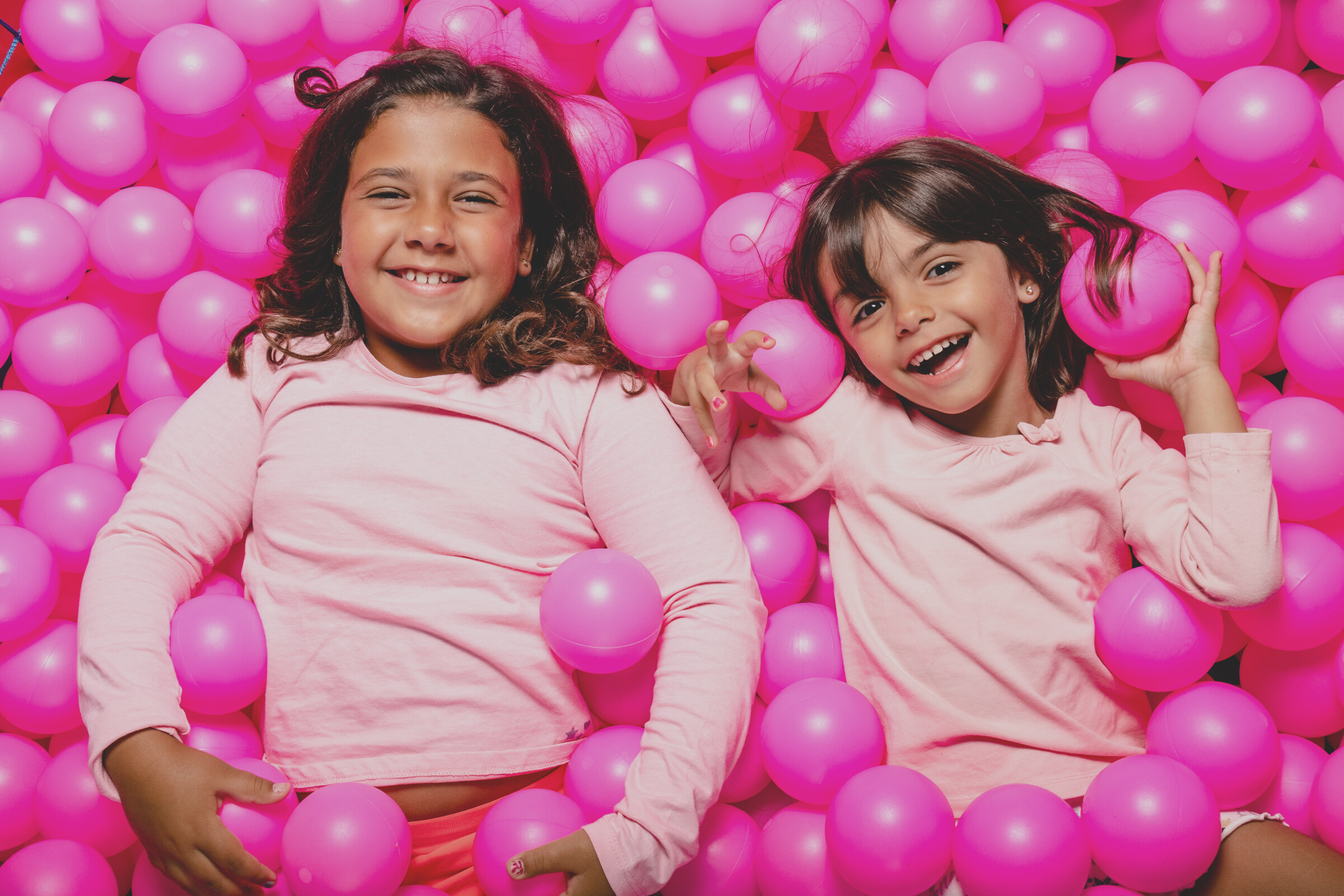 Portrait Of Sisters Sitting Amidst Pink Balls